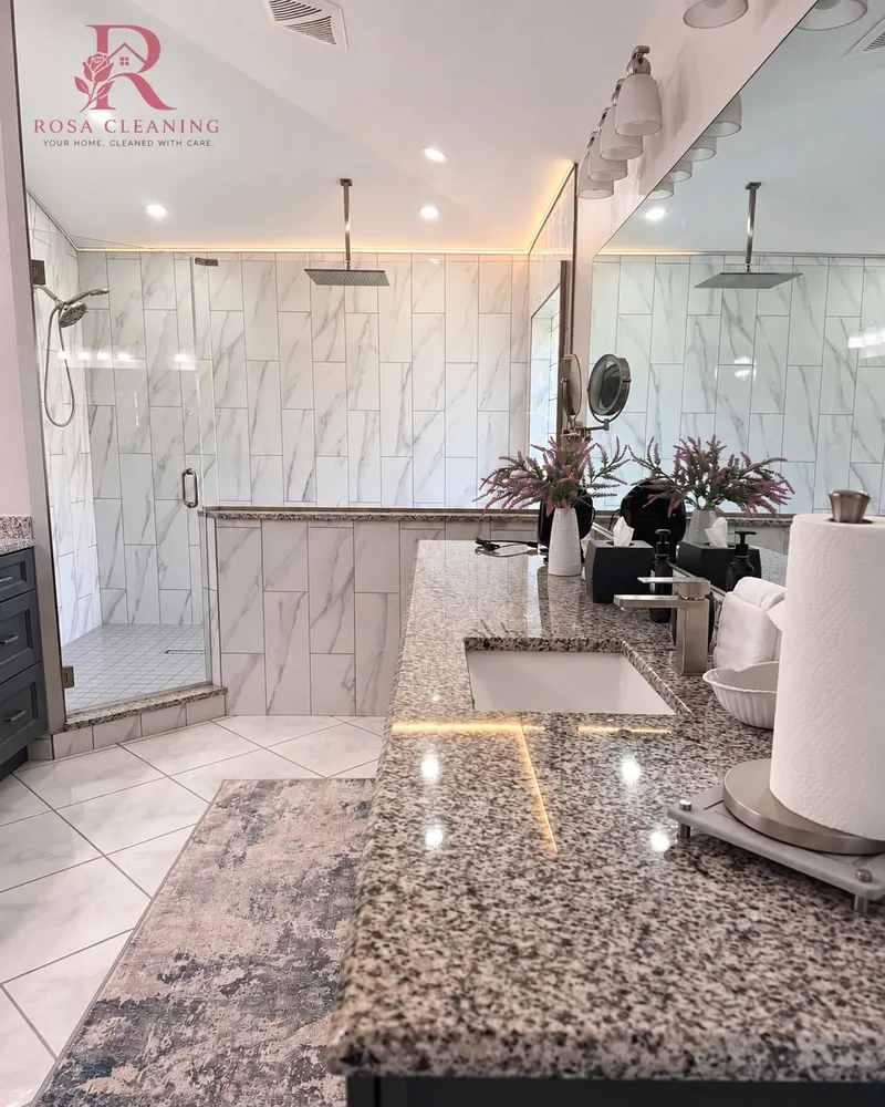Freshly cleaned master bathroom with a glass shower, marble-look tile, and a shining granite counter